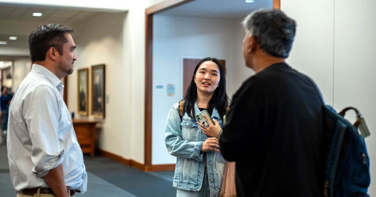 A student chats with Professors Andrew Hayashi and Mitu Gulati