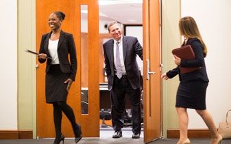 Student leaves an interview room as another student walks in.