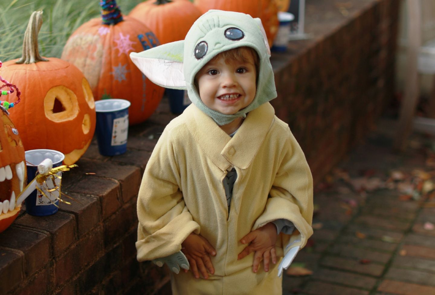 Child in Halloween costume in front of pumpkins