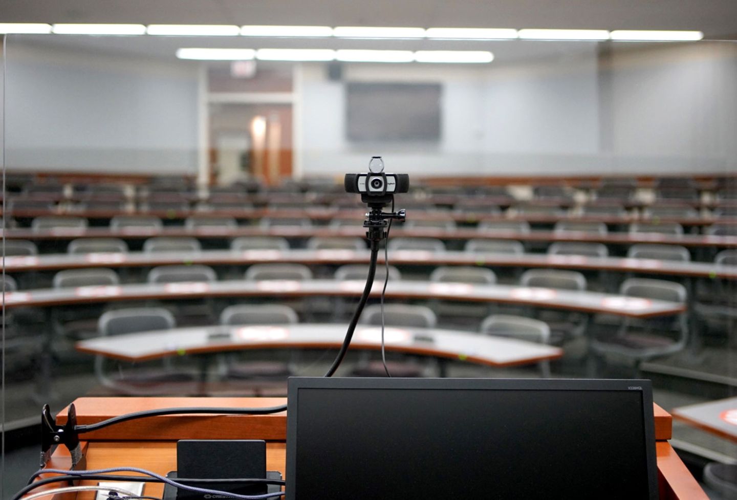 A camera and plexiglass screen at a classroom podium