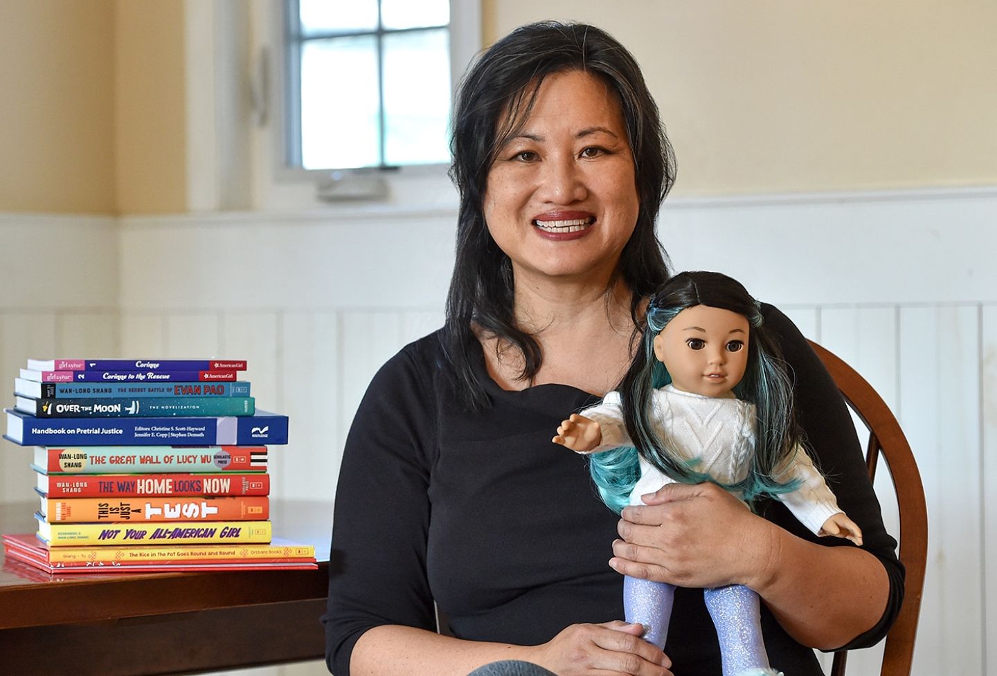 Wendy Wan-Long Shang poses with her books and the American Girl doll Corinne