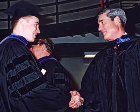 Director Mueller shakes the hand of a graduating student